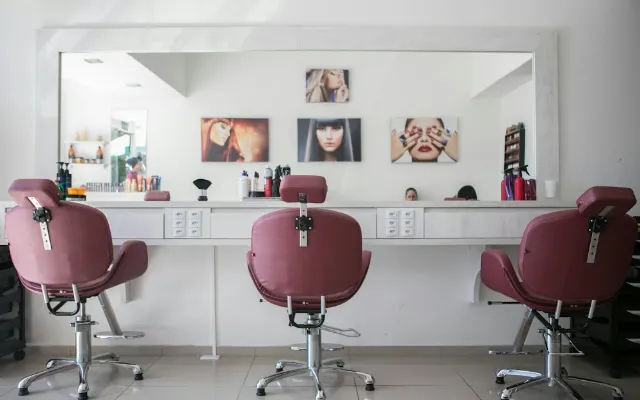 Three styling chairs facing a long mirror in a hair salon